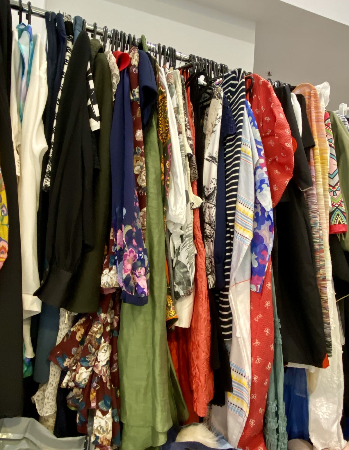Designer jackets, dresses and silk shirts on the rail at Secondo